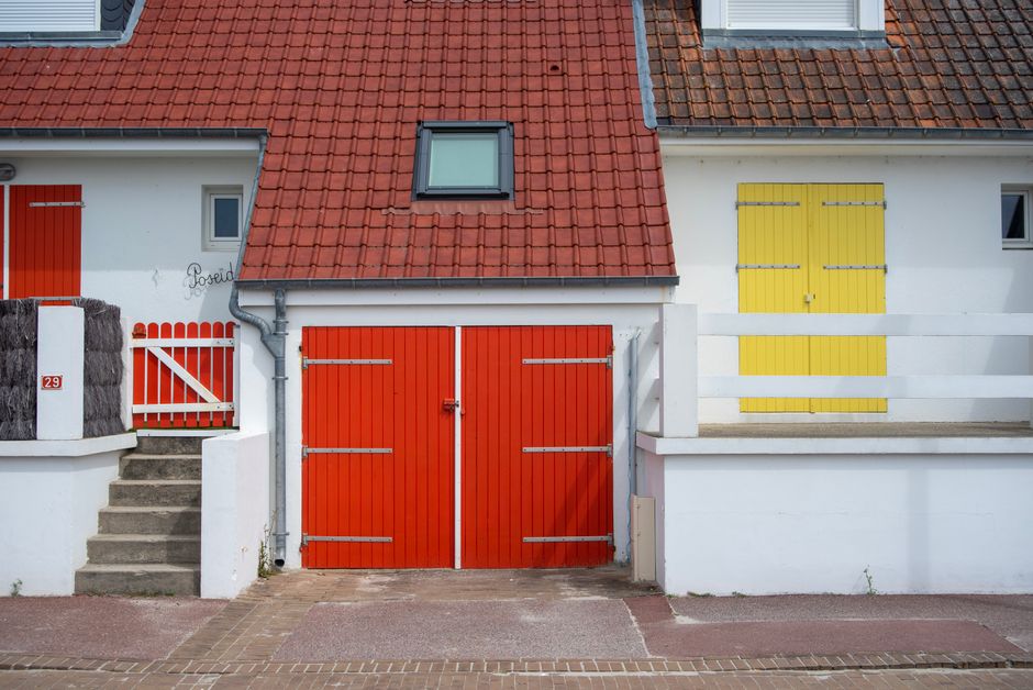 Painted house front with red and yellow doors and a tile roof.