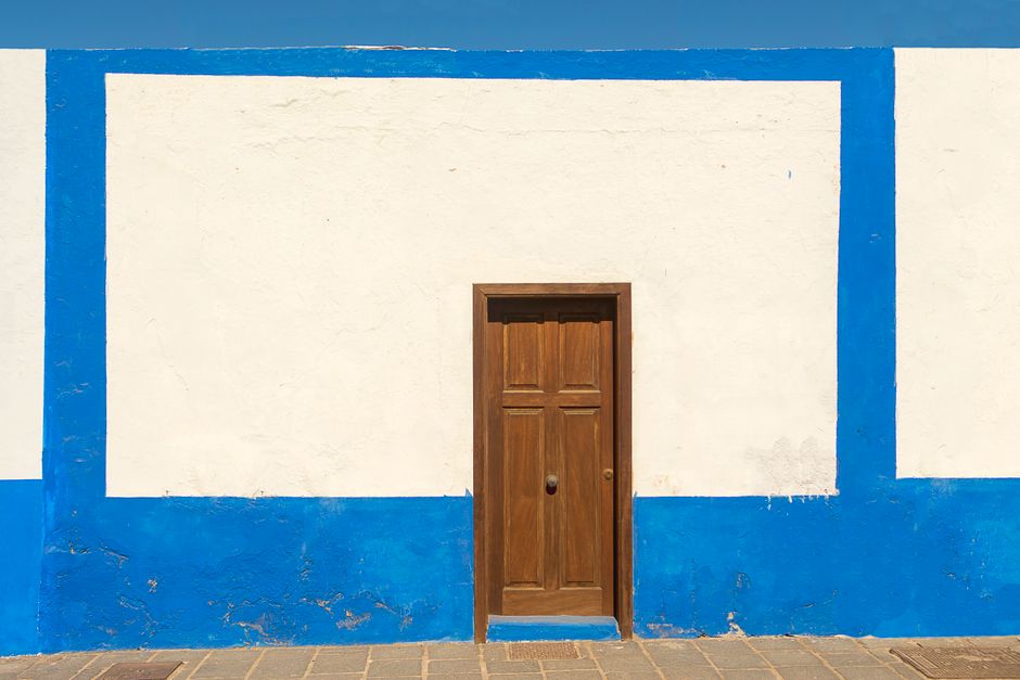 Wooden door in a blue and white painted wall.
