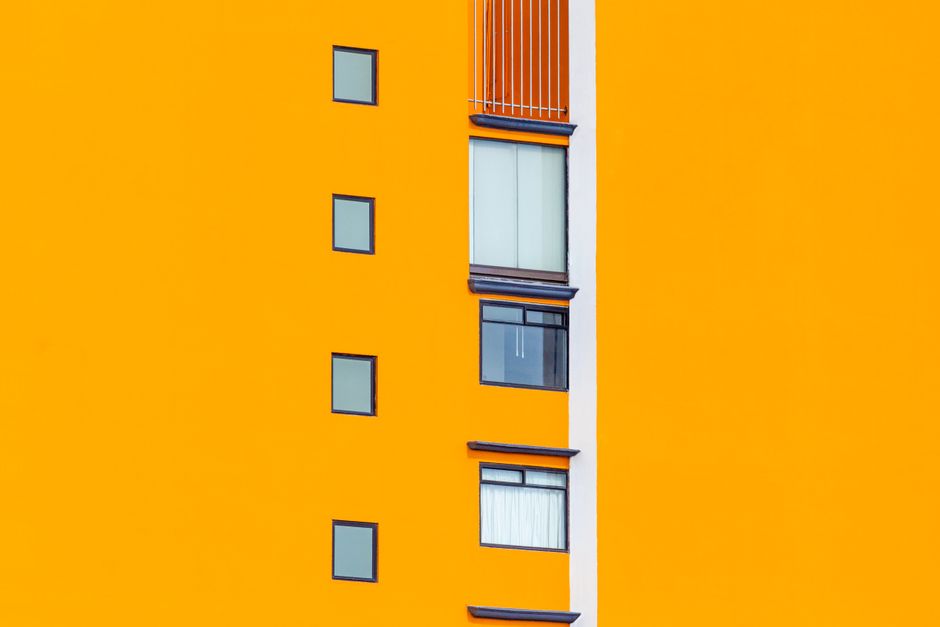 Bright orange painted house wall with small windows.